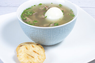 Chicken consomme, traditional Colombian food, accompanied by hard-boiled egg, corn arepas, cilantro and lemon