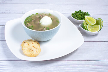 Chicken consomme, traditional Colombian food, accompanied by hard-boiled egg, corn arepas, cilantro and lemon