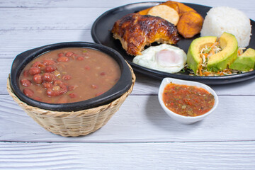 Traditional Colombian lunch, accompanied by chicken, beans, fried egg, arepa, rice, avocado, ripe plantain and salad