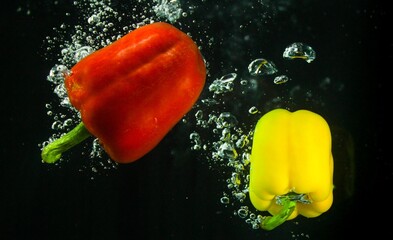 Red and yellow peppers in water with bubbles
