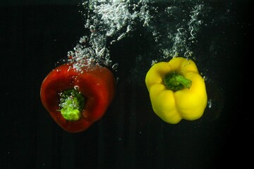 Red and yellow peppers in water with bubbles