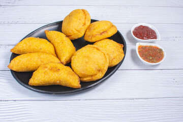 Traditional Colombian snack, chicken empanada with hogao, lemon and sauce