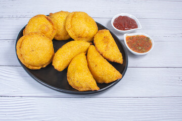 Traditional Colombian snack, chicken empanada with hogao, lemon and sauce