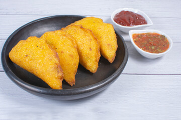 Traditional Colombian snack, chicken empanada with hogao, lemon and sauce