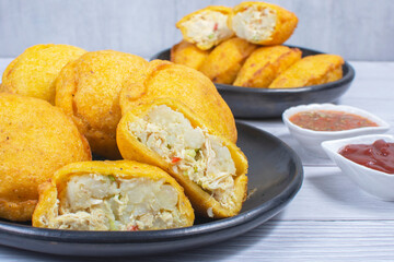 Traditional Colombian snack, chicken empanada with hogao, lemon and sauce