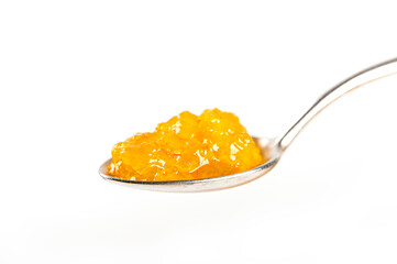 Close up. Orange jam on spoon isolated on white background.