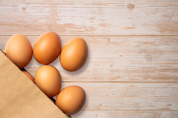 Fresh organic eggs from the brown bag on wooden background.