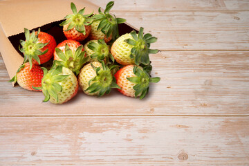 Paper bag with strawberries on wooden background.