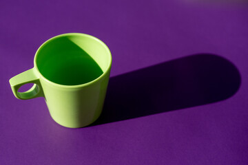 Taza verde en fondo morado. Concepto abstracto.