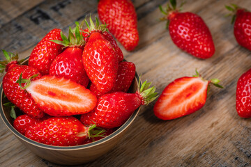 Fresh strawberries in a bowl on wooden table with low key scene