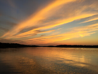 Brilliant sunset over northern Minnesota fishing lake fills sky with colorful clouds and subtle golden hour hues