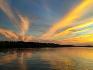 Brilliant sunset over northern Minnesota fishing lake fills sky with colorful clouds and subtle golden hour hues