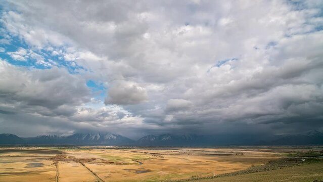 Thick clouds moving in timelapse as the sun lights up the golden landscape in Utah Valley during Spring.