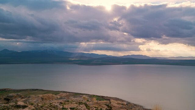 Storm clouds moving in the distance as light rays shine to the ground looking past Utah Lake.