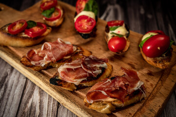 Arrangement of a selection of different tapas or bruschettas on a wooden board. Mediterranean food concept.