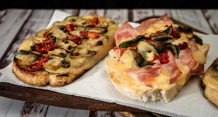 Large bruschettas with cheese, mushrooms, prosciutto and tomato in different combinations. Mediterranean food concept.High view