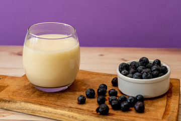 High view of a glass of milk next to some organic blueberries in a modern, stripped-down setting. Healthy eating