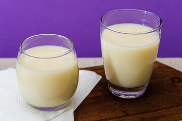 Two glasses of milk of different shape and volume on a wooden board on a table. Healthy drink. high view