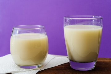 Two glasses of milk of different shape and volume on a wooden board on a table. Healthy drink. high view