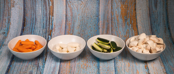 Turned, peeled, chopped vegetables, carrot, turnip, zucchini, mushroom, presented in bowls