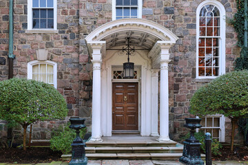 Old stone house with portico entrance and elegant wood grain front door