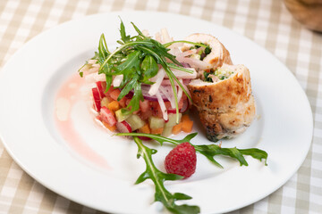 Tartare of fresh diced vegetables and salads in a white plate decorated with a raspberry