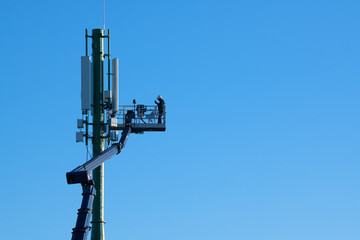 Telecommunications tower with 4G, 5G transmitters, Worker on cellular base station