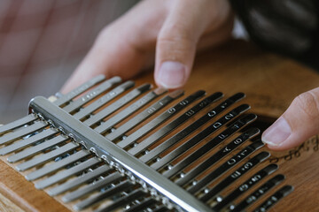 Hand of an Asian girl playing a wooden Kalimba instrument - Powered by Adobe