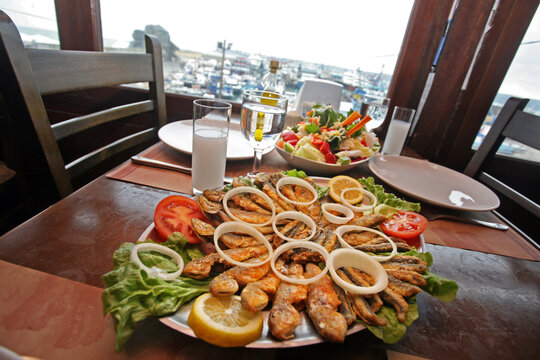Mullet fish (Turkish: Barbun) with salad and raki on the restaurant table.