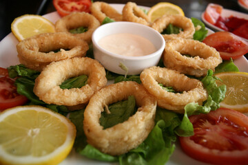 Squid rings with sauce on the dinner plate.