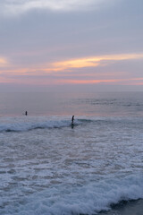 Fototapeta na wymiar Surfers catch waves at sunset in the ocean. Surfing background
