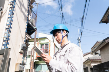 住宅とタブレットを持つヘルメットのビジネスマン