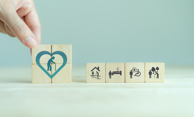 Elderly care concept. Hand holds wooden cubes with icons related to elderly care, medical,...