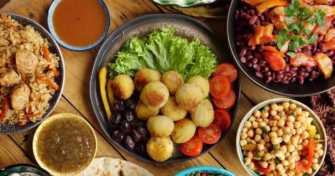 Falafel balls made from ground chickpeas is eaten throughout the Middle East and is a common street food. Women's hands serve a table for iftar dinner during Ramadan