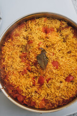 Paella rice dish with tomato, bay leaf, prawns