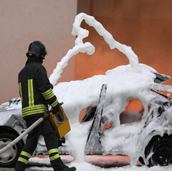 firefighter throws the foam to put out the fire of the crashed car after the accident