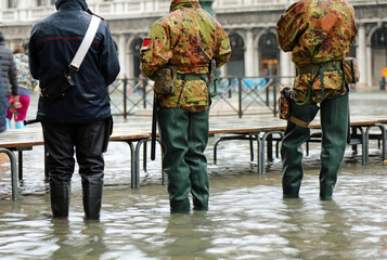 Italian guards and soldiers with high rubber boots patrolling the island of Venice at high tide