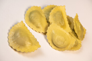 Tasty raw ravioli with flour and spinach on white background, process of making italian ravioli