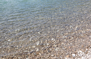 clean clear water of the sea or of the alpine lake with the gravelly bottom with many pebbles