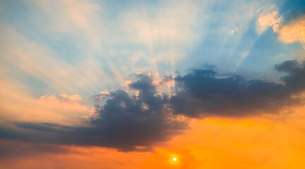 Blue and orange sunset sky with rays of sun. Sun rays slipping through clouds while sun sets.