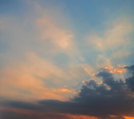 Blue and orange sunset sky with rays of sun. Sun rays slipping through clouds while sun sets.