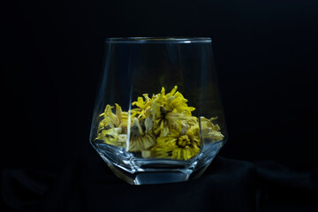 glass of liquors on a black background There are yellow dried flowers in glass of liquor