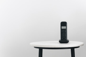 Landline phone standing on small table in room - obrazy, fototapety, plakaty