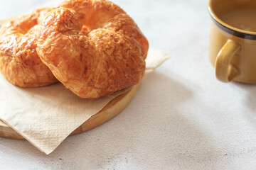 A croissant served with coffee is placed on a white table.