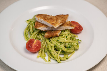 Turkey cutlet and Green spinach spaghetti with cheese and tomato on wooden table