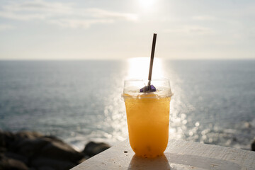 Orange juice on table seaside during sunset sky.