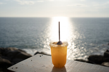 Orange juice on table seaside during sunset sky.