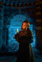 Fototapeta premium Girl with a candle near the dark castle stone wall in the night