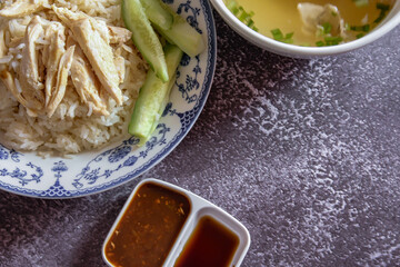rice steamed with chicken soup served in a Chinese style plate with soy sauce and broth on a gray table