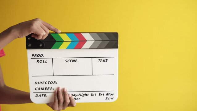 holding Movie clapper board against white wall 